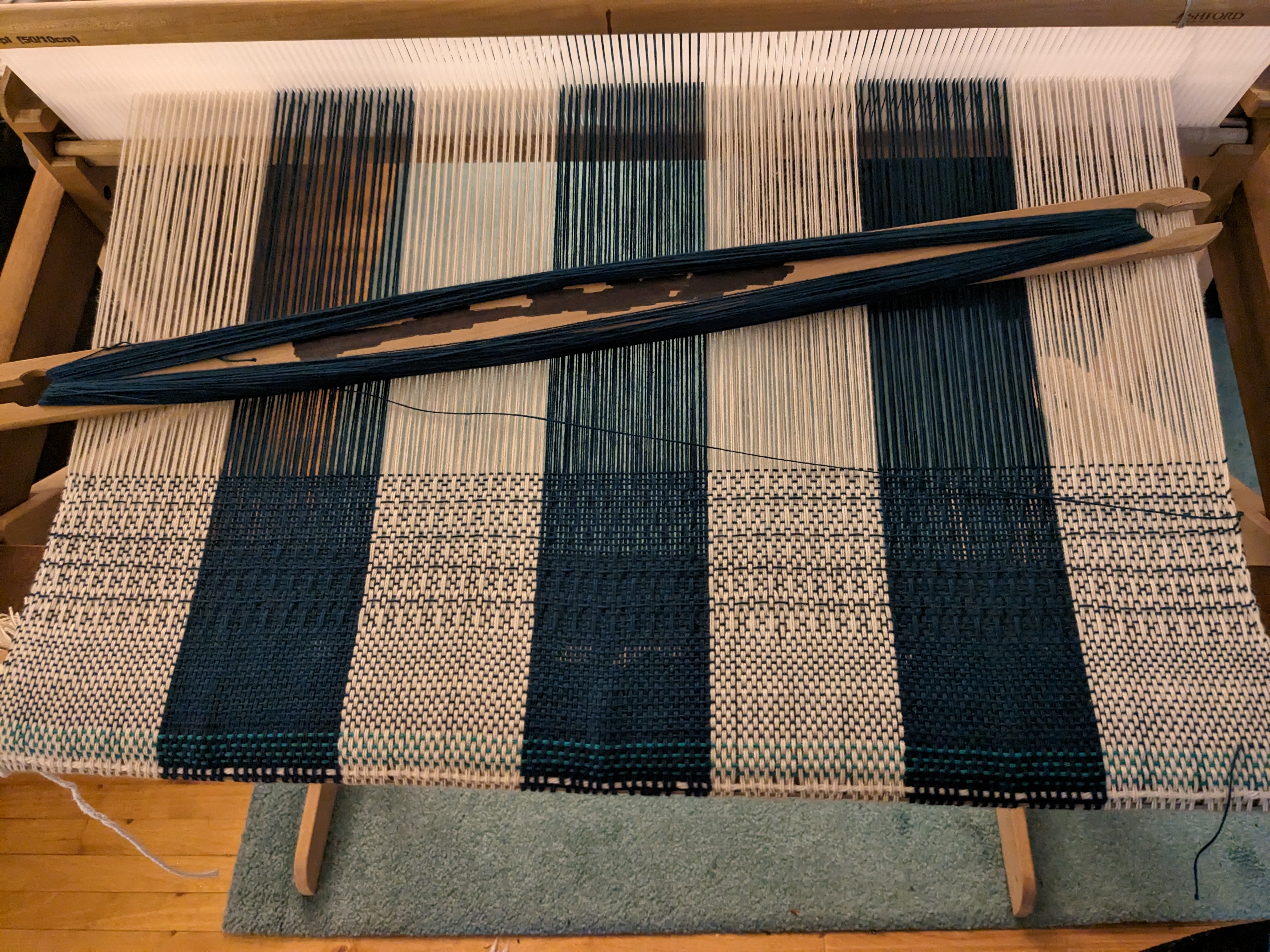 A few inches of weaving a blue and natural buffalo check pattern with pick up