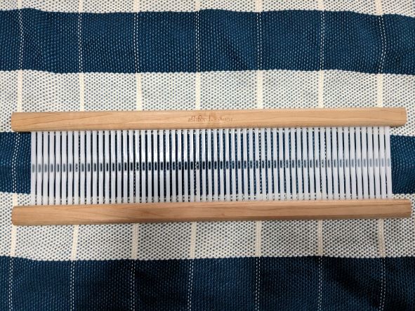 A rigid heddle from a rigid heddle loom, showing the slots and holes